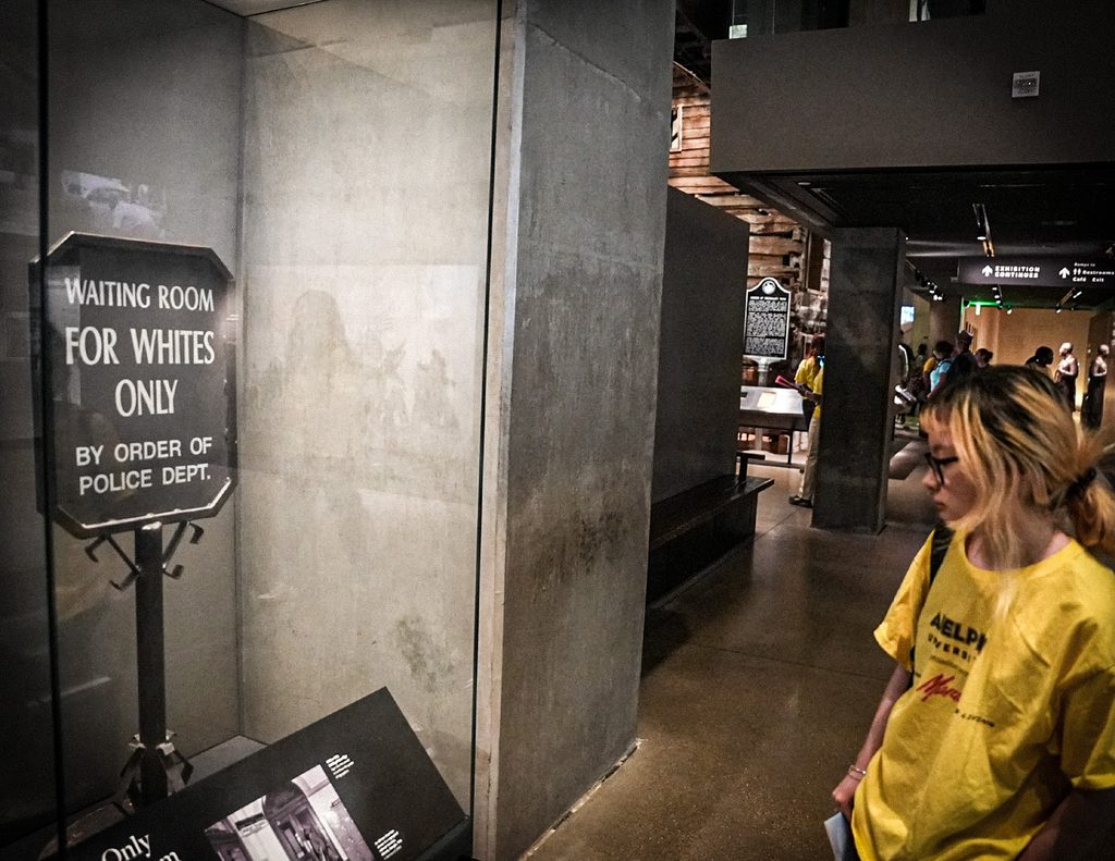 A Two Museums Program participant viewing a historic segregation sign in a museum exhibit.